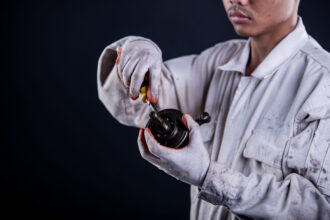 Car mechanic wearing a white uniform stand holding wrench isolated on gray background with copy space.