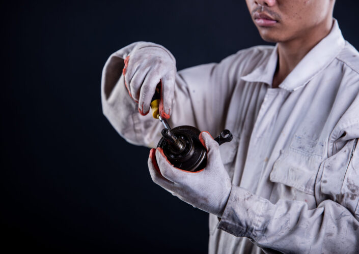 Car mechanic wearing a white uniform stand holding wrench isolated on gray background with copy space.