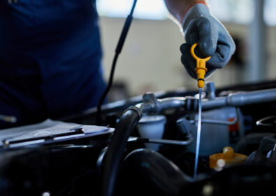 Close-up of a mechanic checking car oil in auto repair shop.